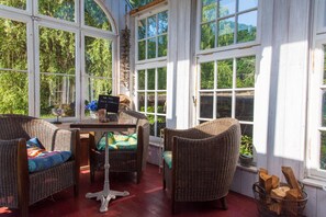 A sunroom with wicker furniture, a table, and a sign indicating a price of $39. - Circus wagon by the river (Windeck)