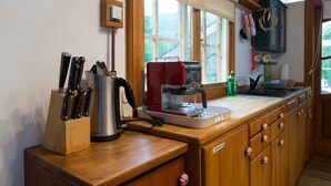 A kitchen with a coffee maker, knives, and a window.