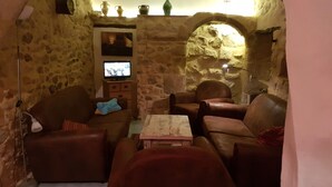 Une pièce aux murs de pierre, avec des canapés en cuir, un téléviseur et une petite table.