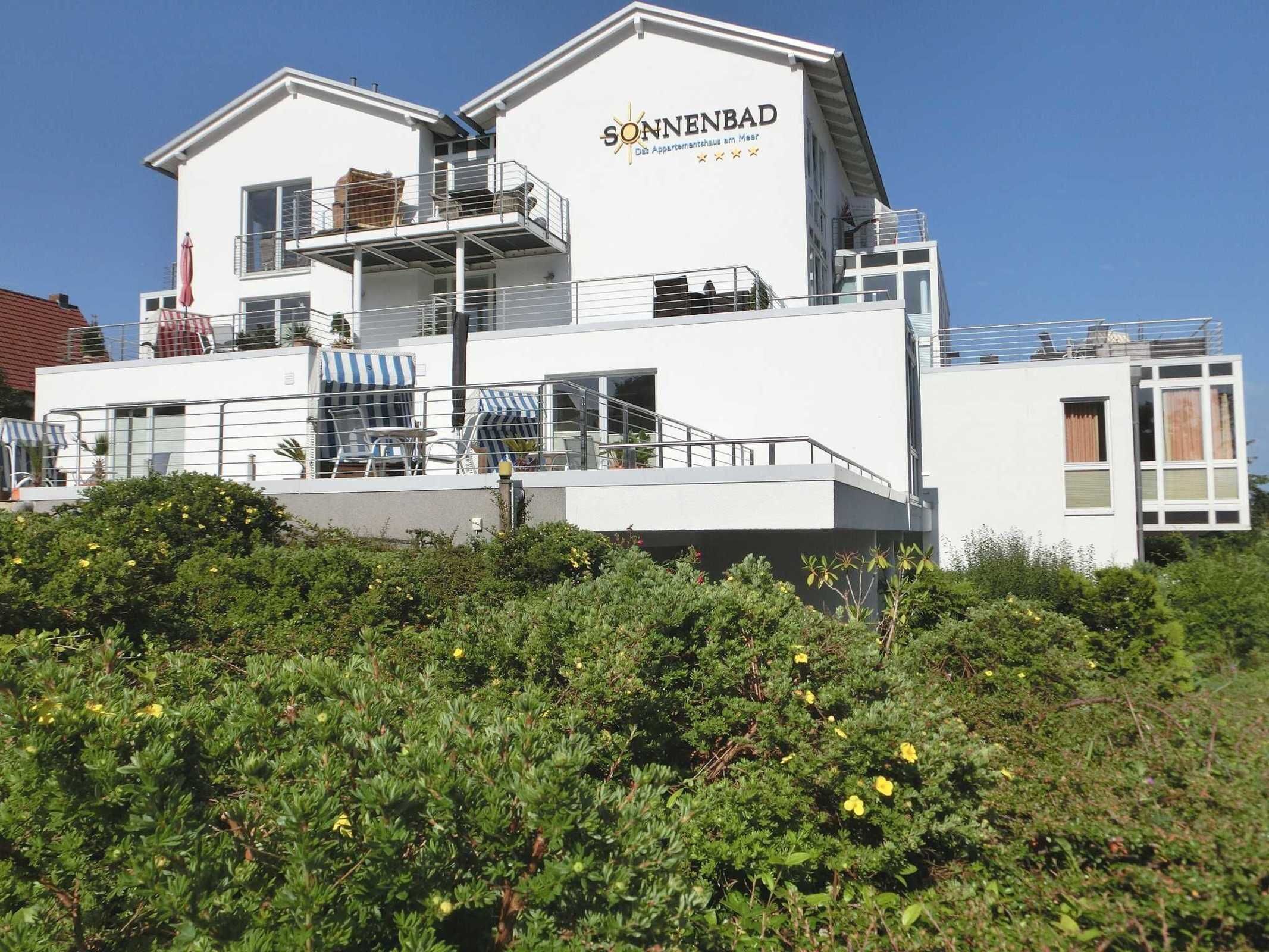 A modern building with a sign reading "Sonnenbad" and balconies with outdoor seating.