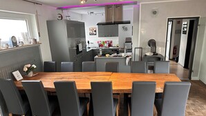 Une cuisine moderne avec des meubles de couleur grise, une table à manger en bois et des chaises noires.