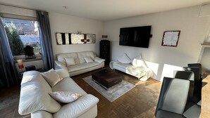 Un salon moderne avec un canapé blanc, une table basse et un téléviseur fixé au mur.