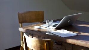 Un bureau en bois avec un ordinateur portable, un verre d’eau, une souris et des papiers.