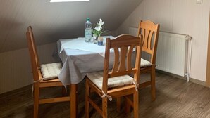 A small, cozy attic room with a slanted ceiling, a skylight, a table with chairs, and a radiator. - Vacation, rest and relaxation in a relaxing natural (Rappin OT Helle)