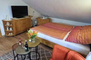 A bedroom with a bed, a television, a small table with drinks, and a fan. - Peace and relaxation in a restful natural setting (Rappin OT Helle)
