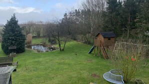 A backyard with a wooden playhouse, a small pond, a Christmas tree, and a metal bench. - Vacation, rest and relaxation in a relaxing natural (Rappin OT Helle)
