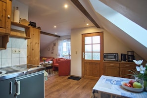 A kitchen with a microwave, coffee maker, and a dining table with a fruit bowl.