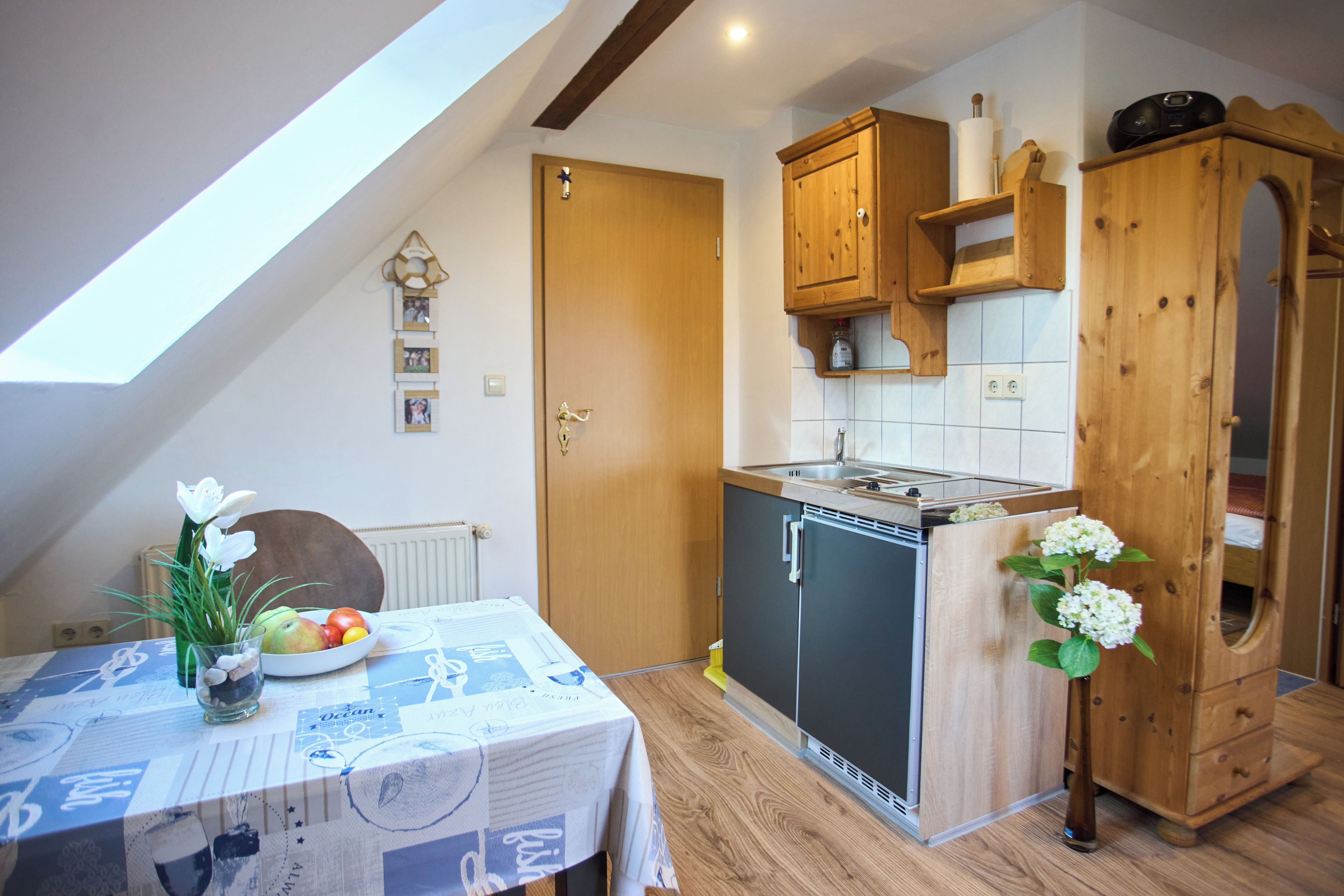 A compact kitchen with a built-in stove, wooden cabinets, and a small dining area with a table set for two.