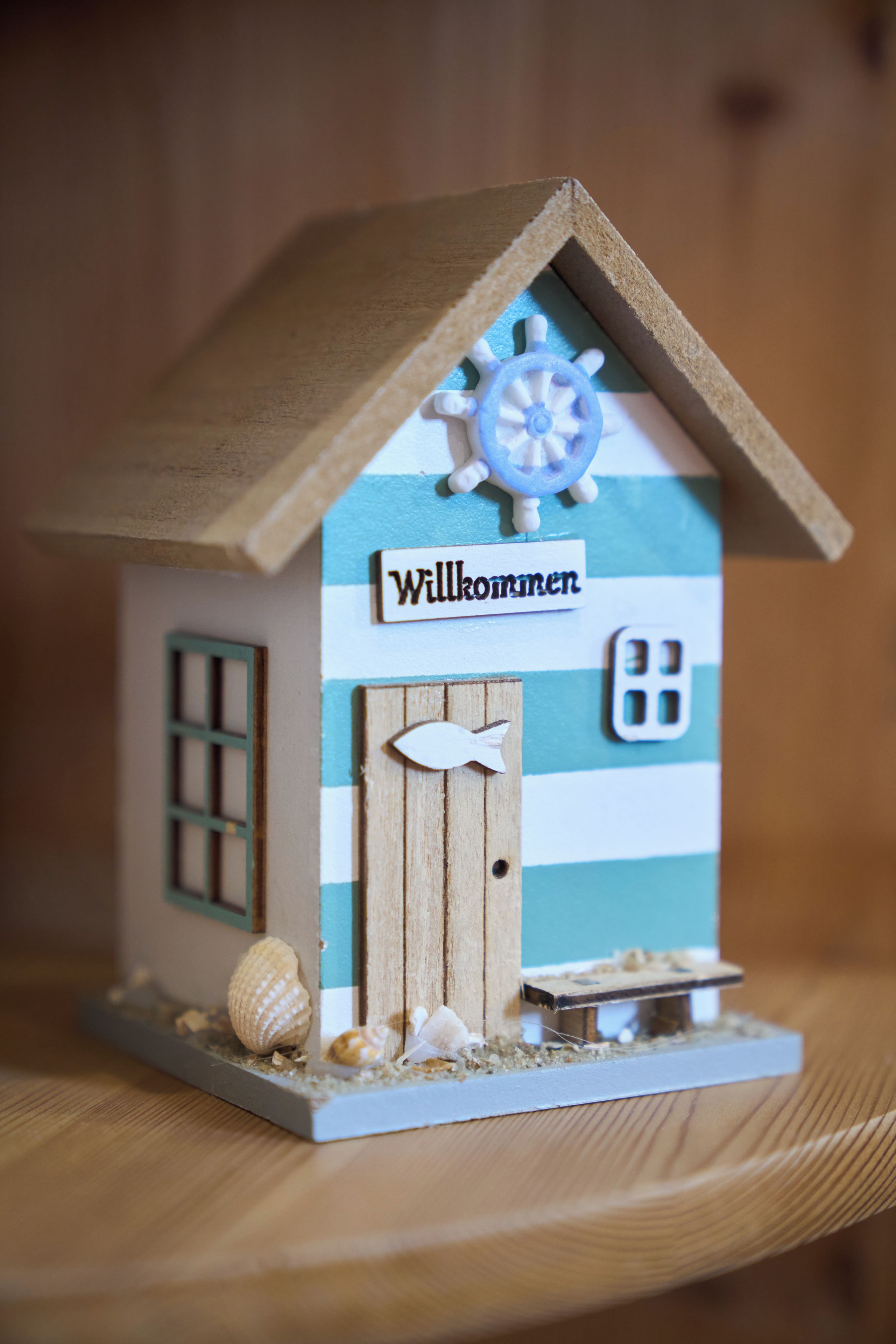 Une petite maison en bois avec une pancarte sur laquelle on peut lire « Willkommen » (Bienvenue).