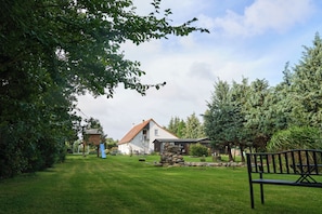 A house with a large lawn, a wooden play structure, and a stone wall. - Peace and relaxation in a restful natural setting (Rappin OT Helle)