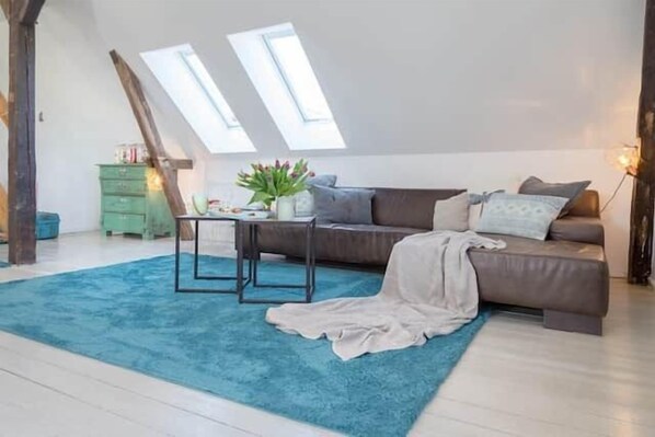 Une pièce de style loft avec un canapé, une petite table et un tapis bleu.