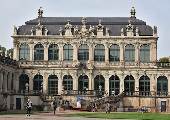 En imponerende bygning i klassisk arkitektur, med en central kuppel, mange buede vinduer og statuer på taget.