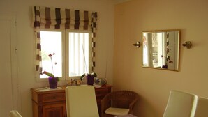 Un coin repas avec une table dressée pour deux personnes, une radio et un miroir au mur.