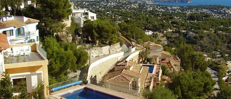 A residential area with a swimming pool, houses, and a view of the sea.