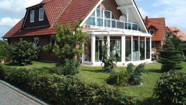 Ein Haus mit geneigtem Dach, großen Fenstern und einem gepflegten Rasen.