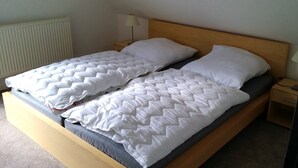 Ein Doppelbett mit Holz Kopfteil, zwei weiße Kissen und einer gesteppten Decke.