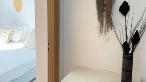Huoneessa on sänky, työpöytä laatikoineen ja seinälle ripustettu makrame-seinäkoriste.