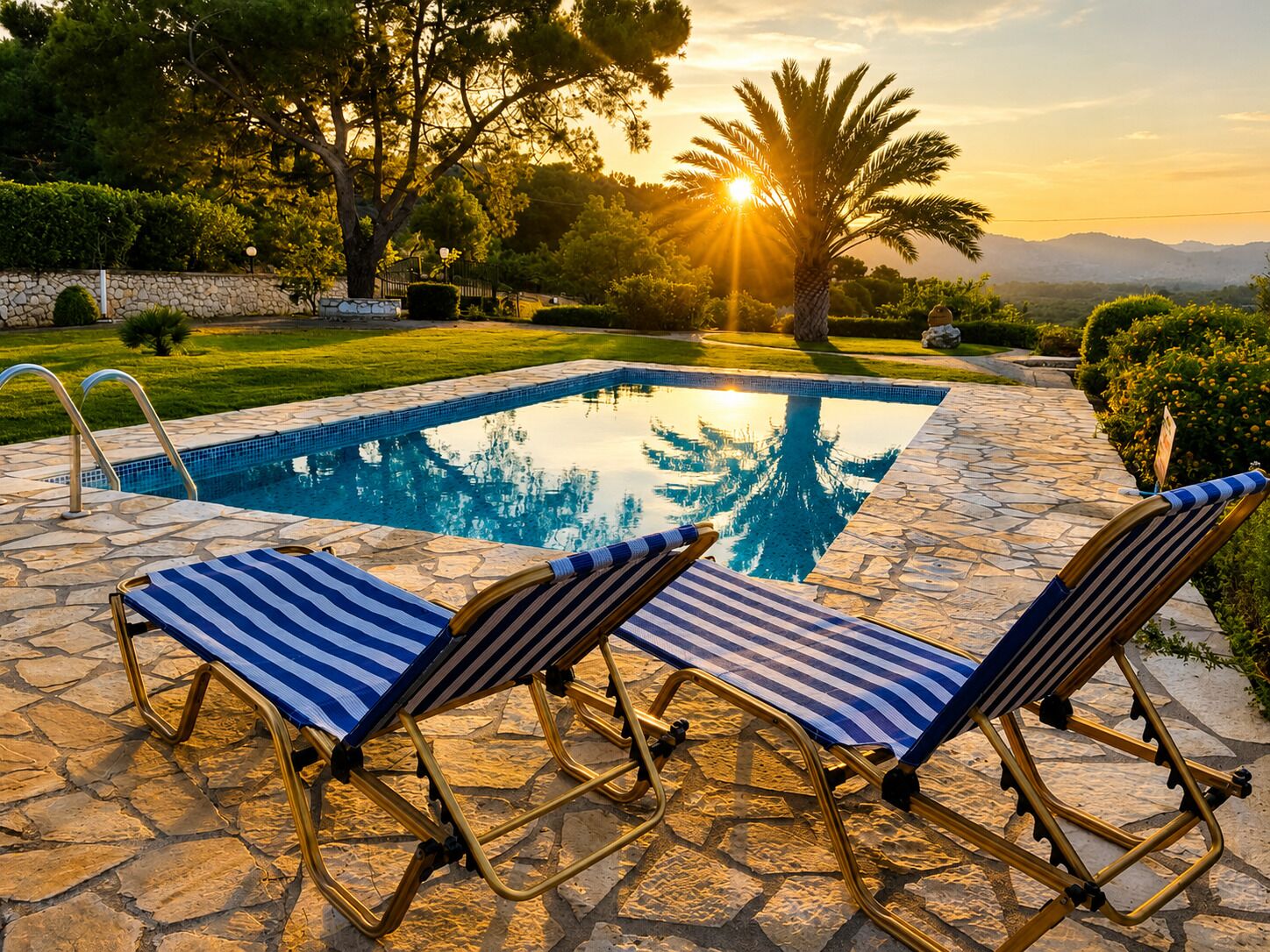 Un espace aménagé au bord de la piscine, avec une terrasse en pierre, deux chaises longues à rayures et un palmier.