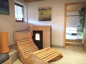 Ein Zimmer mit einer hölzernen Bank, einem Kamin, einem Gemälde und Blick ins Freie.