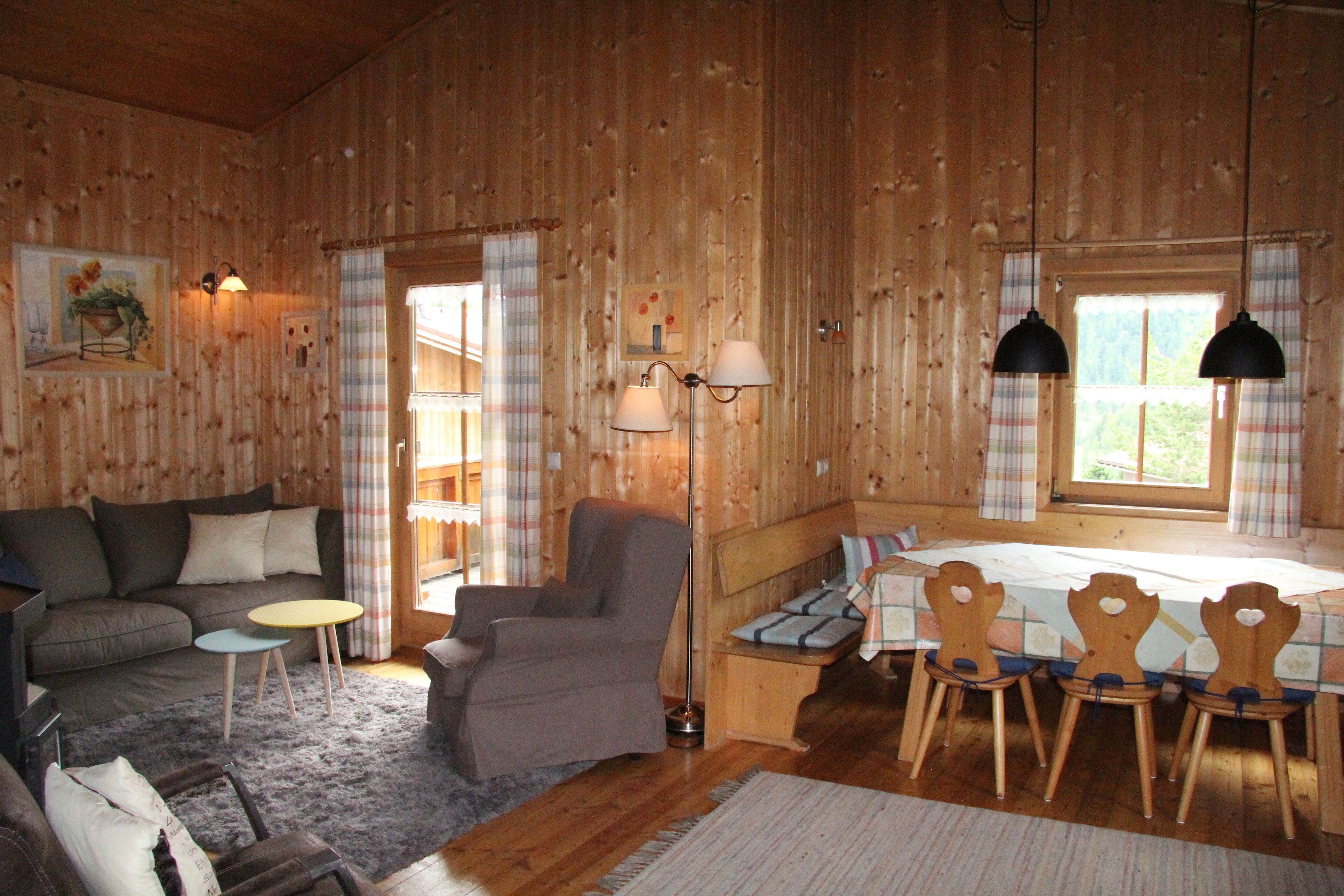 Ein gemütliches Cabin-Interieur mit einer Couch, einem Sessel, einem Esstisch und Stühlen.