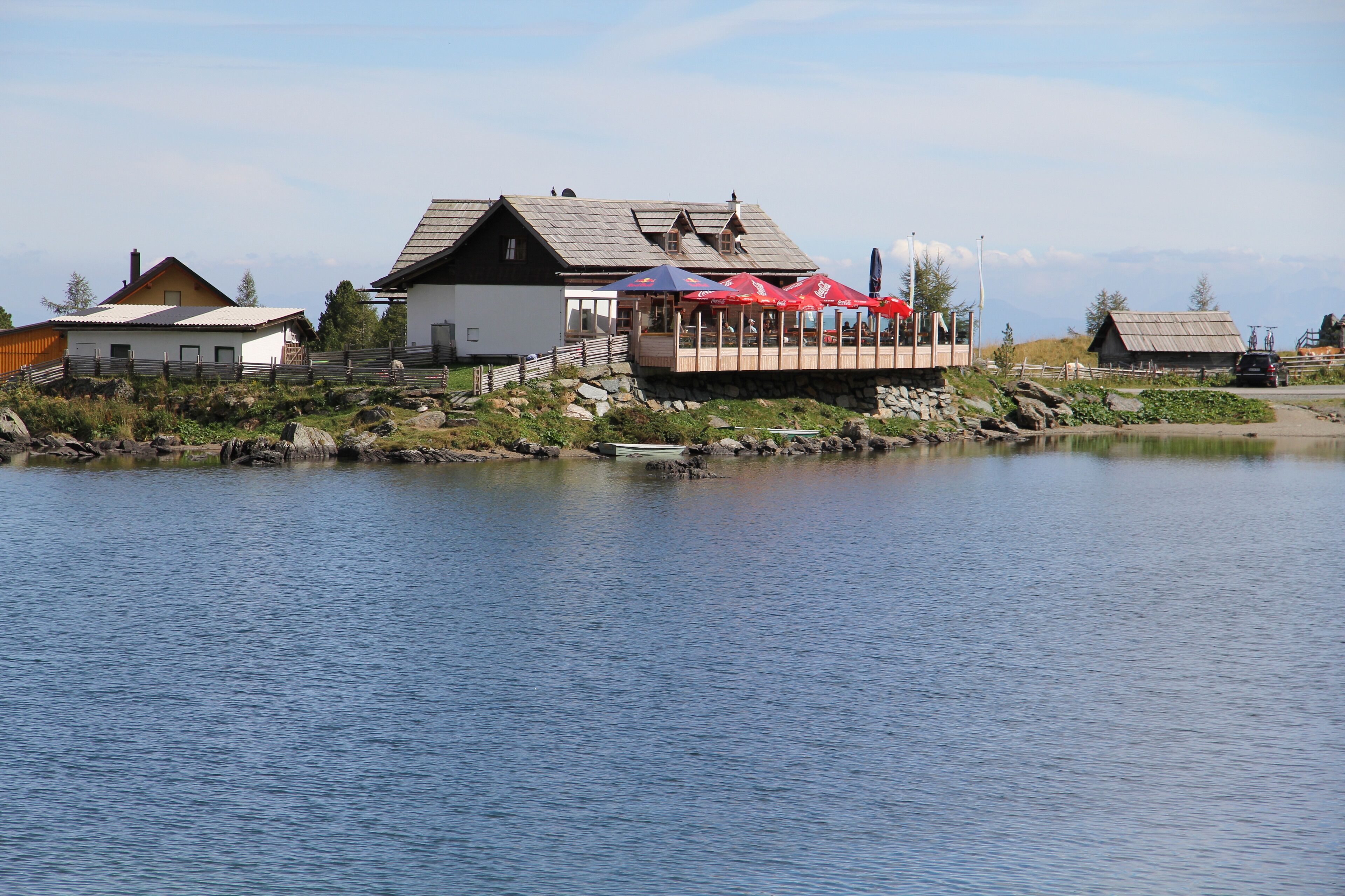 A lakeside building with a dock and outdoor seating area.