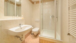 Une salle de bain avec une douche à parois de verre, un lavabo et des toilettes.
