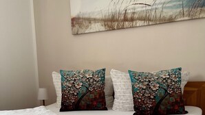 A neatly made bed with white linens and two decorative pillows with floral patterns. - 5min beach & forest, sunny, single storey (Prerow)