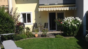 A two-story house with a patio area, a small garden, and two lounge chairs. - Free mobility with public transport! (Zell am see)
