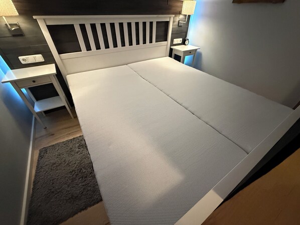 Un dormitorio moderno con una cama blanca, una mesita de noche, un escritorio y una lámpara.