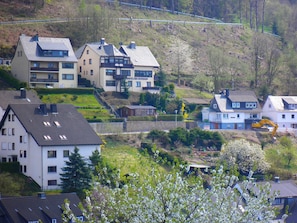 A residential area with multiple two-story houses, a visible construction vehicle, and a hilly landscape in the background. - ☀️☀️☀️ cozy apartment with additional room to expand (Willingen)