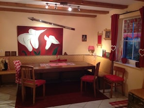 A dining area with a large floral painting, wooden furniture, and a window with heart-shaped decorations. - ☀️☀️☀️ cozy apartment with additional room to expand (Willingen)
