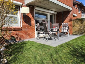 Une maison en briques dotée d’un patio aménagé avec du mobilier d’extérieur et un petit jardin.