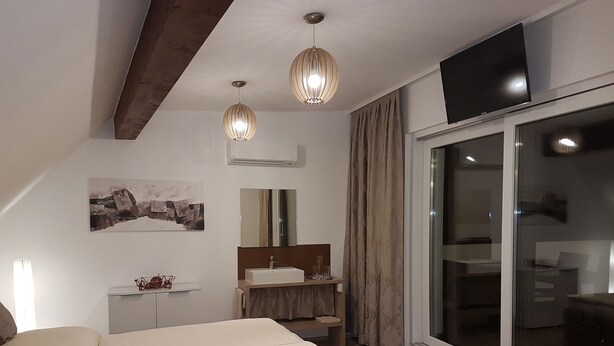 Une chambre moderne avec un grand lit, une table de chevet, un miroir, un lavabo et une télévision.