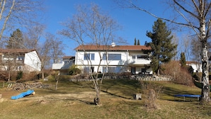 A two-story house with a sloped roof and a balcony on the upper floor. - Quiet 67 m² apartment in the beautiful green of Bad Urach (Bad Urach)