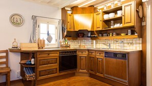 A kitchen with wooden cabinets, a dishwasher, and a window with curtains.