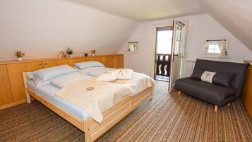 Un dormitorio con una cama de madera, un sofá gris y una alfombra colorida a rayas.
