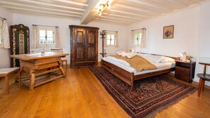 A bedroom with a wooden bed, a large wooden table, and a traditional rug.