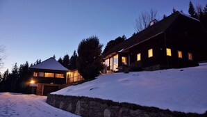 A two-story house with a stone wall and snow-covered ground.