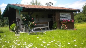 Eine rustikale Chalet mit geneigtem Dach, einer Holzdiele und einer Bank.