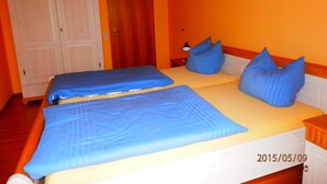 Ein Zimmer mit zwei Betten, einem Holzschrank und einer Tür.