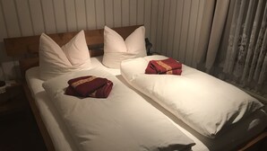 A hotel room with a wooden headboard, white bedding, and two red towels with a logo. - Small and cozy holiday home. Quiet Location (Bunde)