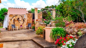 Un espace extérieur aménagé dans un style rustique, avec des murs en pierre, des plantes en pot et une pergola.