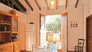 Un coin repas avec une table dressée pour quatre personnes, un réfrigérateur, des placards en bois et une vue sur l’extérieur.