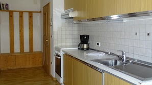 Uma cozinha moderna com armários de madeira, pia de aço inoxidável e cafeteira.