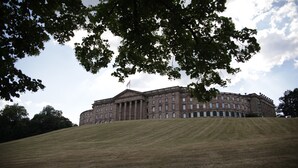 Un grand bâtiment historique à l’architecture classique, situé sur une colline verdoyante.