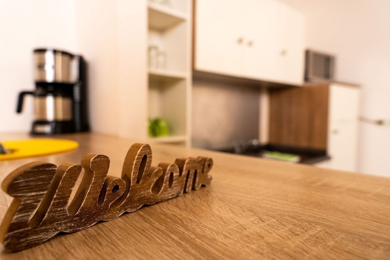 Un letrero de madera que dice 'Welcome' sobre una mesa de madera en una cocina.