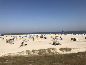 Ein Strand mit vielen blauen und bunten Strandhütten, einem klaren Himmel und einem weiten Blick auf das Meer.