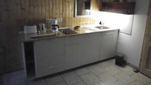 Eine kleine Küche mit Holzwänden, einem Spülbecken, einer Kaffeemaschine und einem Spiegel.