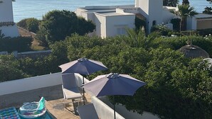 A rooftop pool area with lounge chairs and umbrellas, overlooking a clear blue sea. - House by the sea, private pool, sea view, roof terrace, air conditioning, WLAN, sep. Studio (Cala Serena)