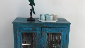 A teal-colored cabinet with glass doors, a small figurine on top, and a few decorative items on the top shelf.